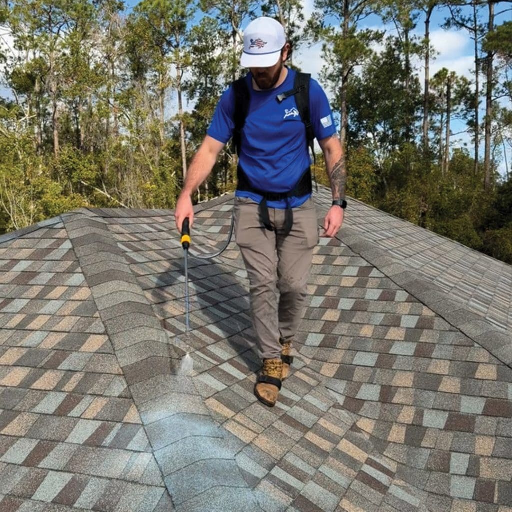 Florida roof rejuvenation technician spraying Shingle RX sealer down slope of asphalt shingle roof with backpack sprayer
